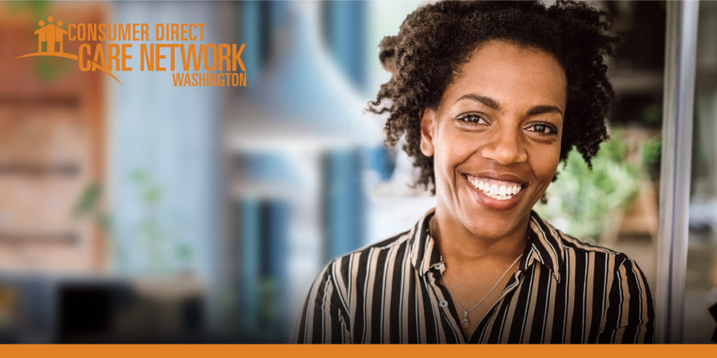 African American Woman in a striped shirt smiling in her office.